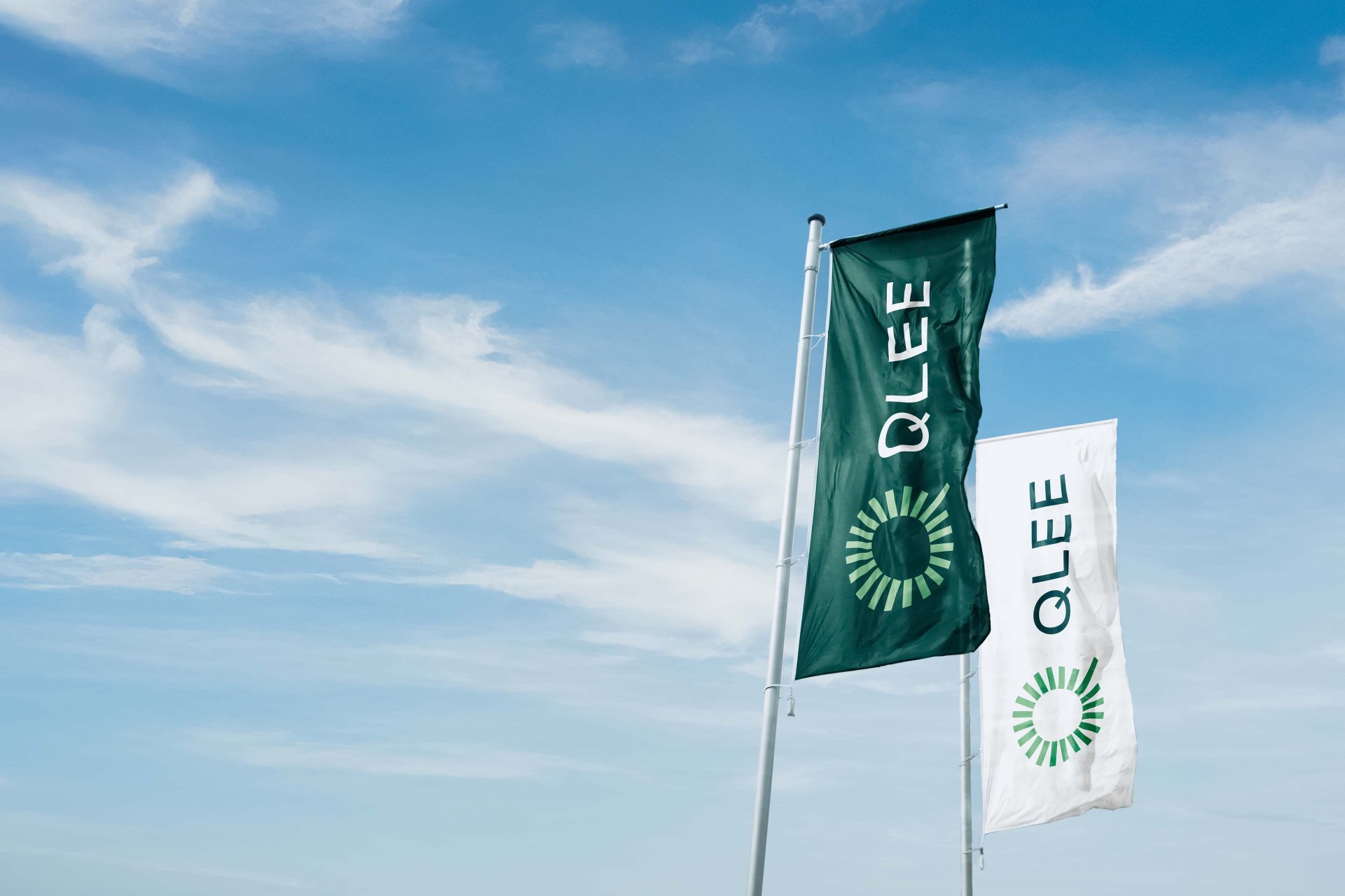 Zwei Flaggen mit dem Logo von QLEE vor blauem Himmel.
