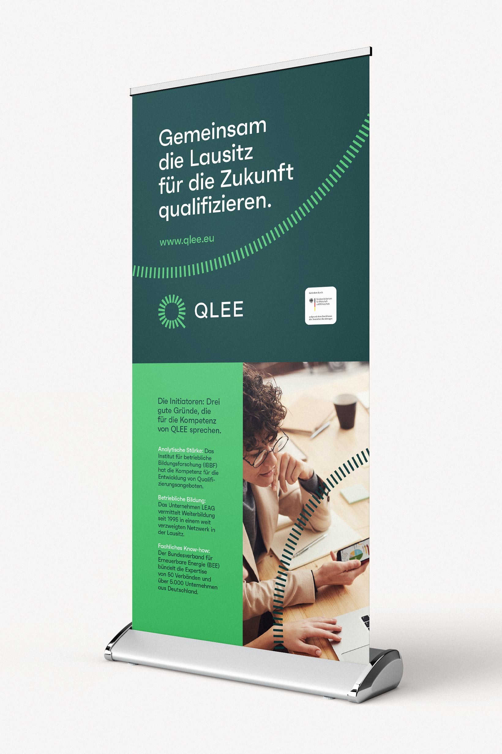 QLEE-Roll-up mit Verbundinformationen und Fotomotiv für Messe- oder Veranstaltungsanwendungen.
